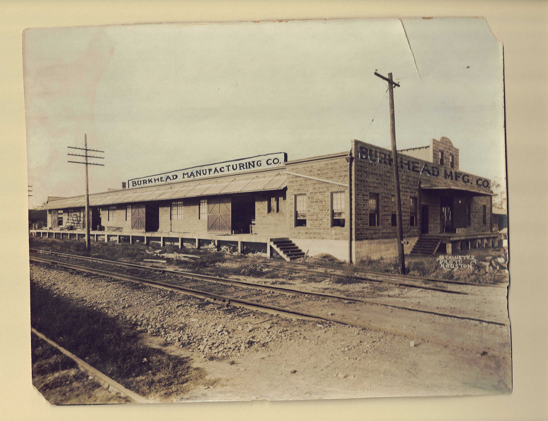 Old photo of the Burkhead Manufacturing Co. building with railroad tracks in front of it